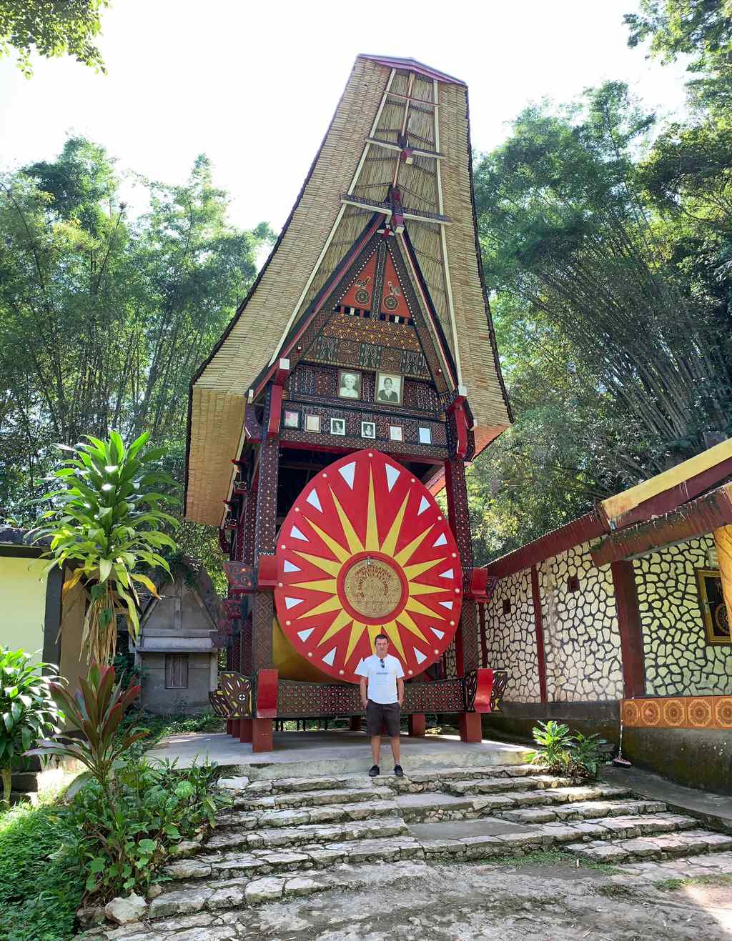 Portail sculpté au disque solaire rouge et portraits de famille encadrés à Ke'te Kesu, Tana Toraja