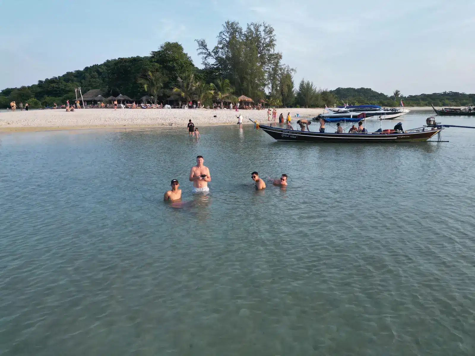Baignade dans l'eau turquoise peu profonde à côté d'un longtail à Ko Mat Sum