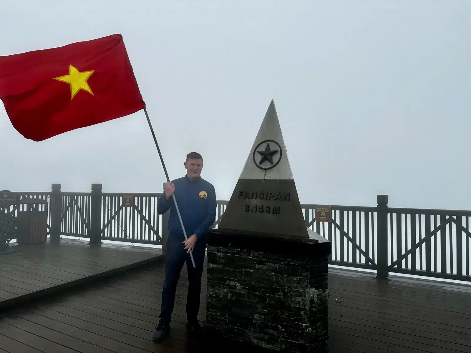 Avec un drapeau vietnamien à côté de la borne du sommet du Fansipan à 3 143 mètres