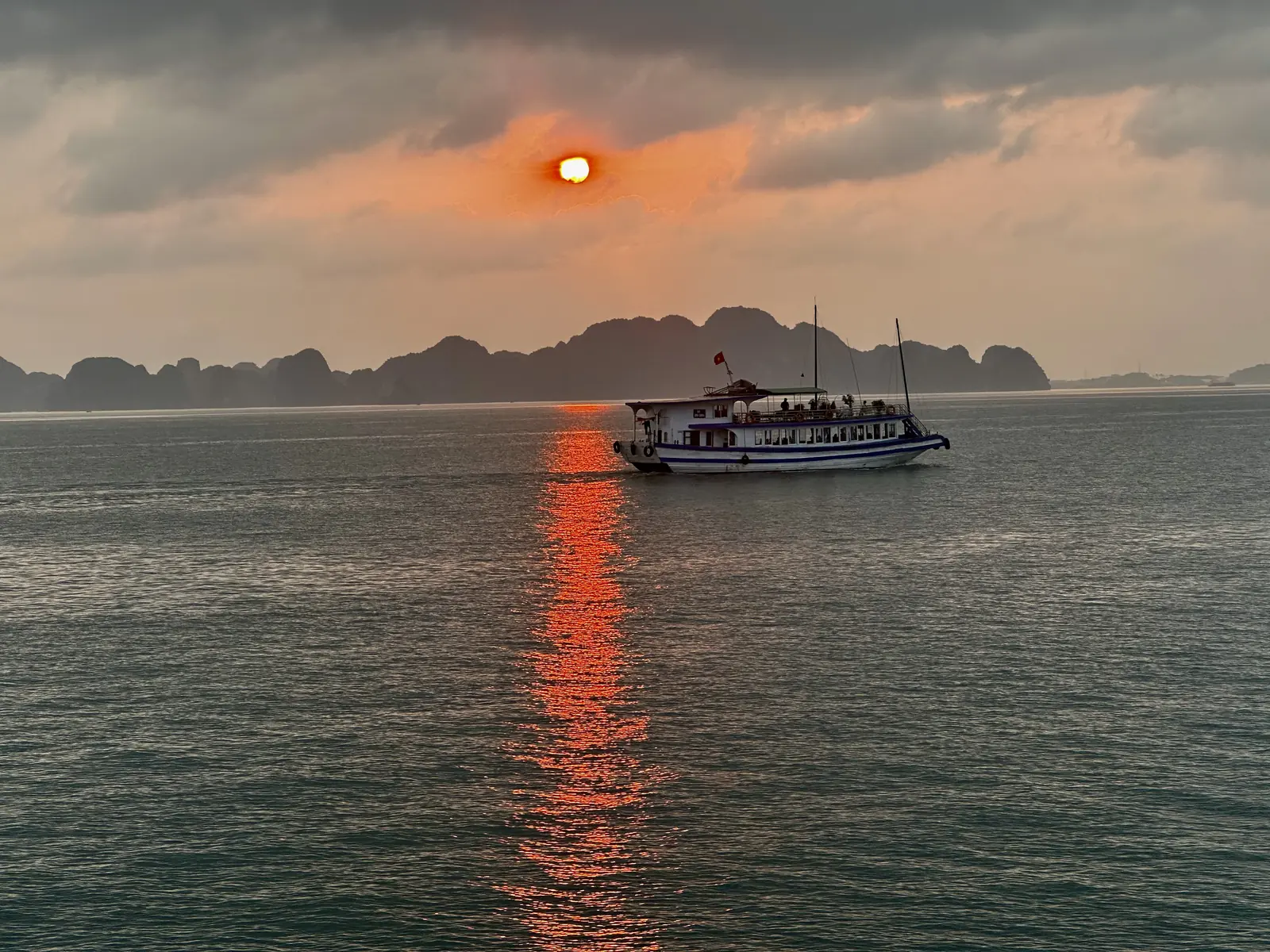 Coucher de soleil sur les îles karstiques de la baie d'Halong depuis un bateau