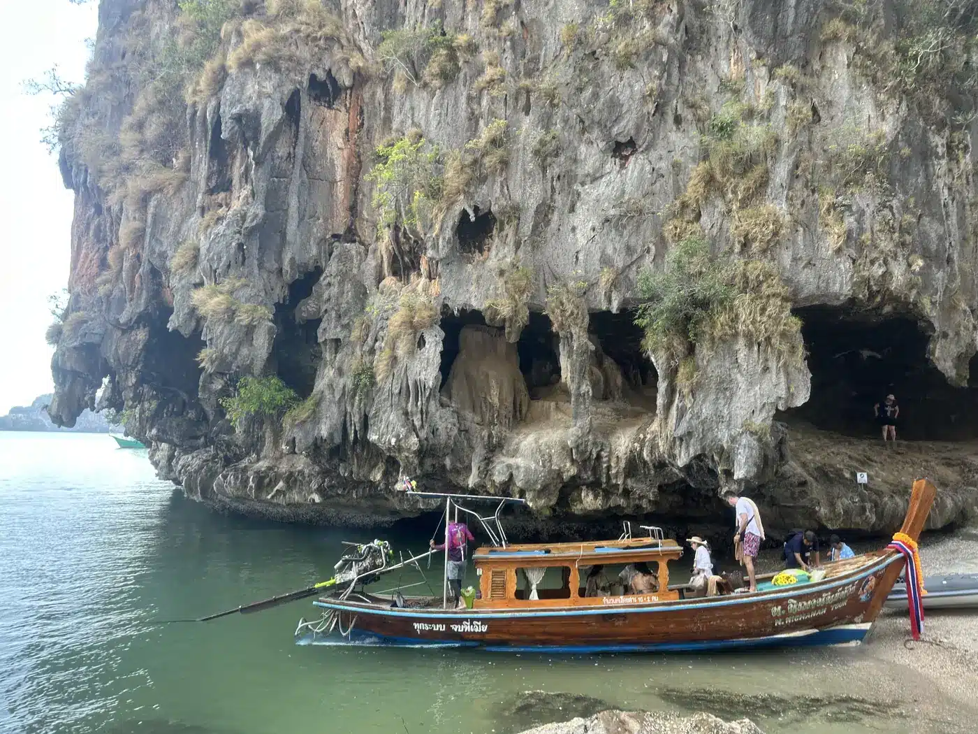 Bateau longtail sous la falaise érodée de Khao Phing Kan, James Bond Island