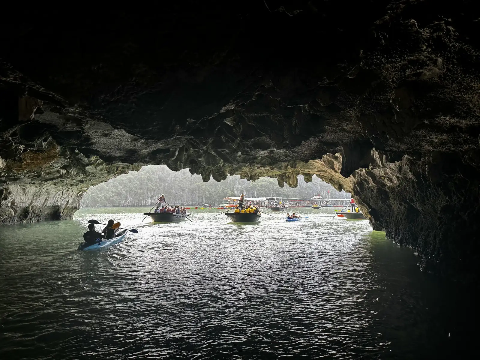 Barques de bambou sous l'arche rocheuse de la grotte de Luon, baie d'Halong