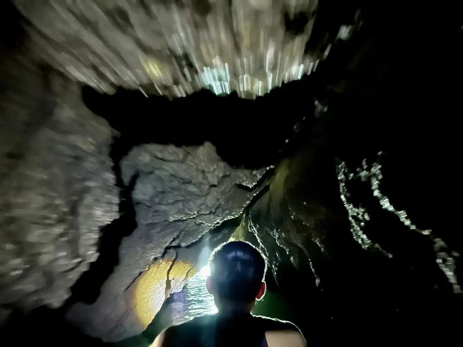En kayak dans une grotte marine plongée dans le noir, éclairée par une lampe frontale, Ko Panak, baie de Phang Nga