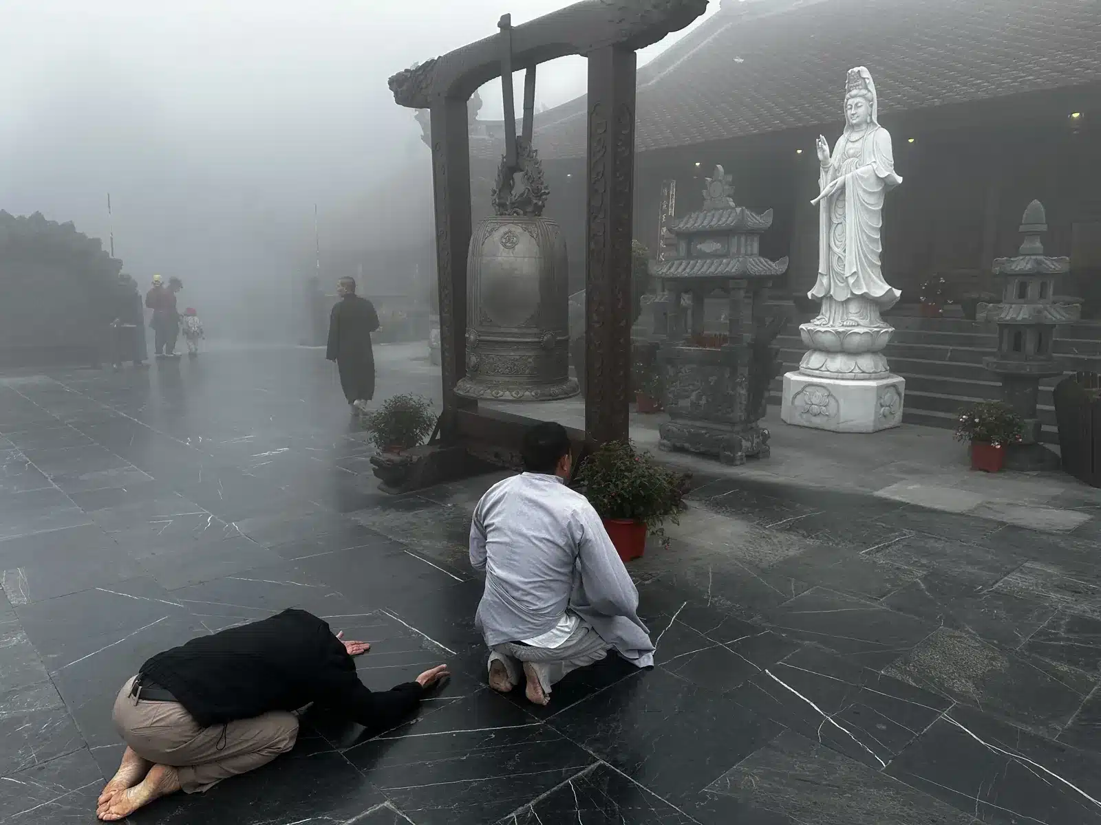Pèlerins agenouillés en prière devant une statue de Guanyin aux pagodes du Fansipan