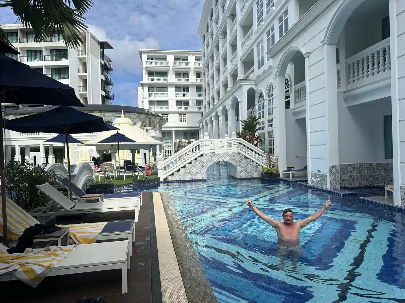 Longue piscine en mosaïque bleue entre les bâtiments blancs du Mövenpick Myth Hotel Patong