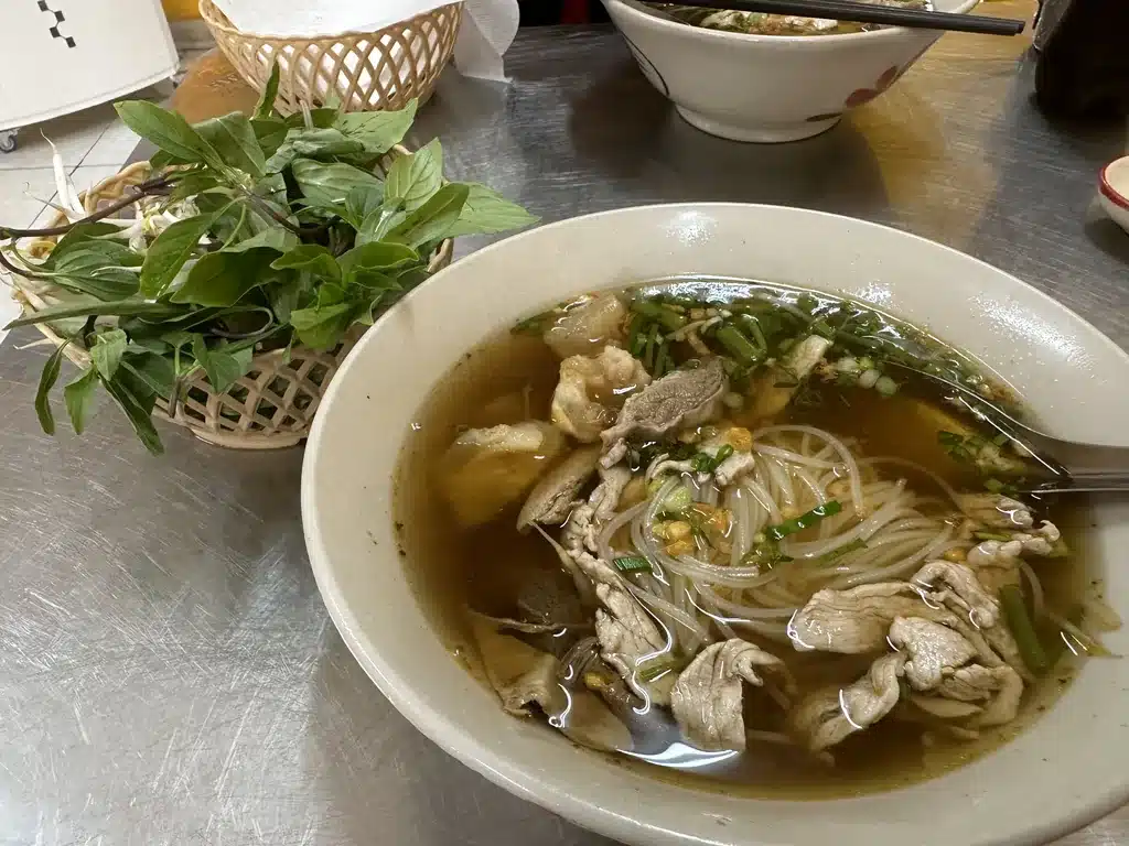 Soupe de nouilles hu tieu au porc et panier d'herbes fraîches à Cholon, Saïgon
